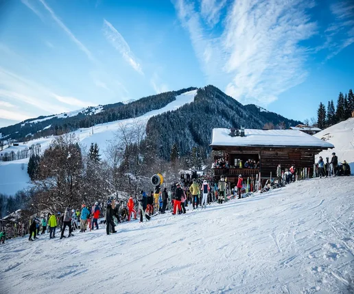 Alm inmitten einer verschneiten Piste mit vielen tanzenden Gästen